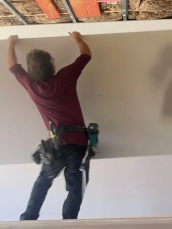 Dan lifting a sheet of plasterboard into place